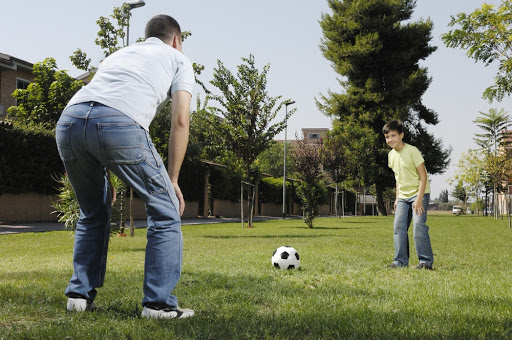 father and son playing football in urban park &#8211; it
