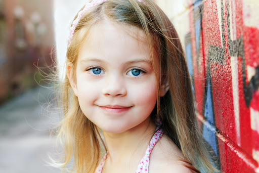 Little girl in an urban setting smiles at the camera. &#8211; it