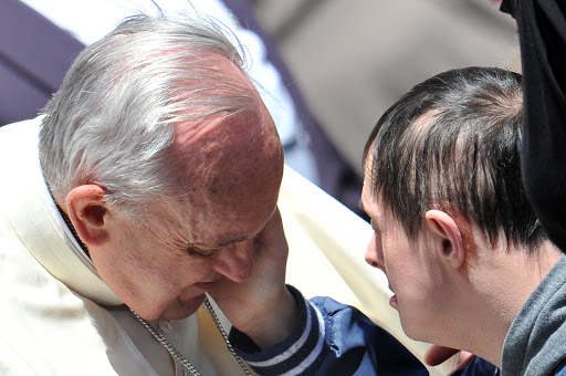 A down&#8217;s syndrome boy caresses Pope Francis