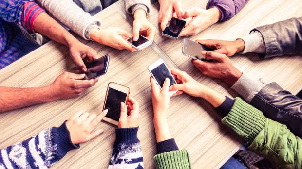 Top view hands circle using phone in cafe &#8211; Multiracial friends mobile addicted interior scene from above &#8211; Wifi connected people in bar table meeting &#8211; Concept of teamwork main focus on left phones