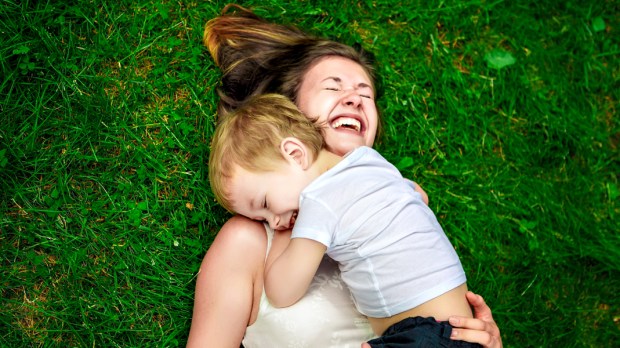 WEB3 MOM AND SON PLAYING GRASS PARK HUG LAUGH Shutterstock