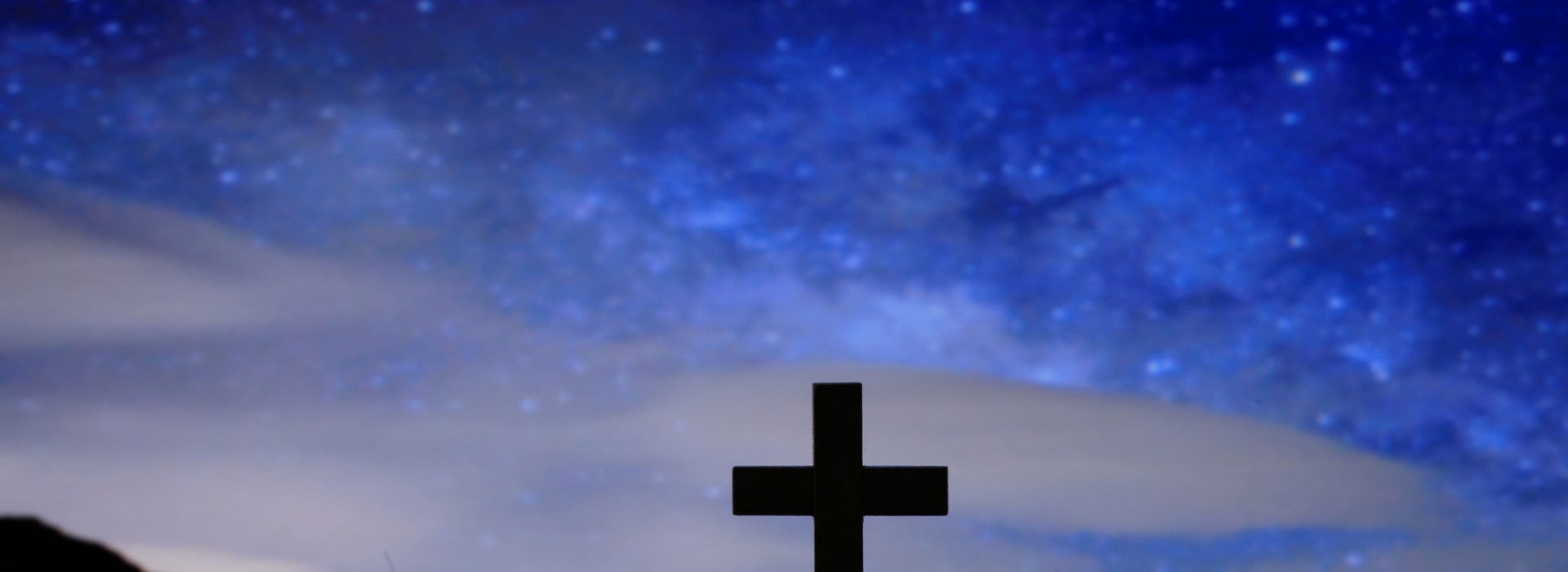 Wood cross over a dark night starry sky