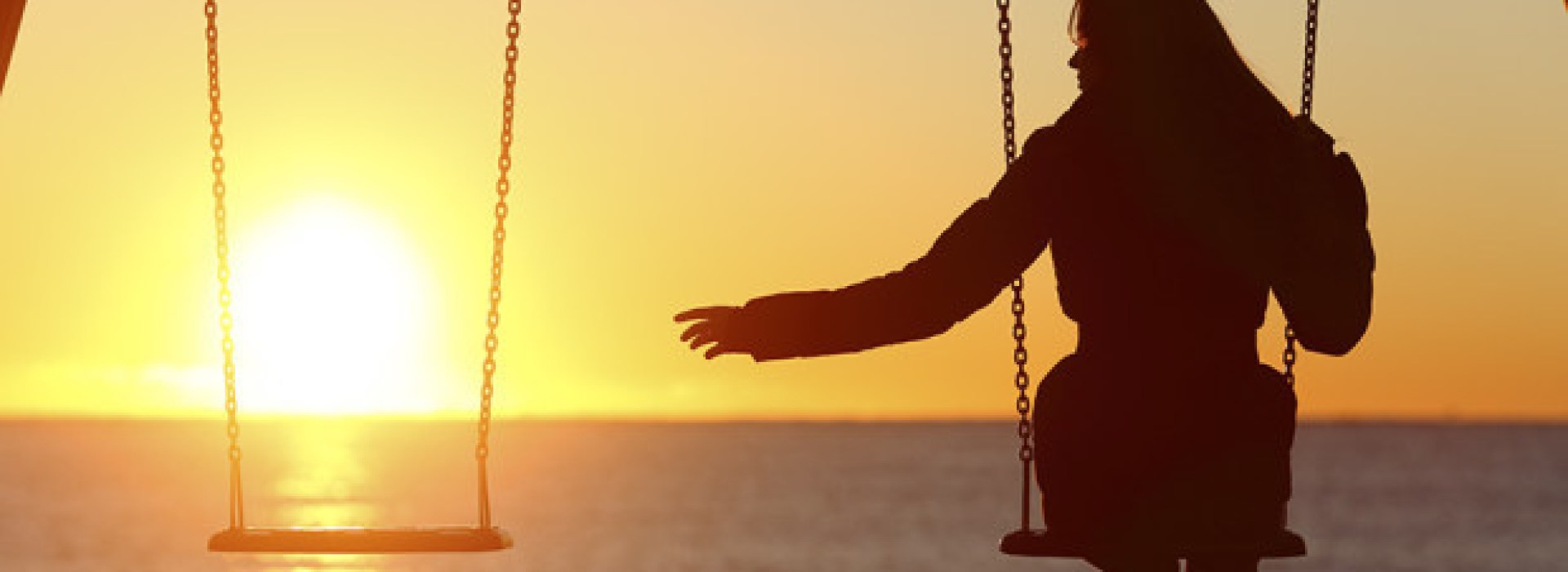 single-woman-swinging-beach-sunset