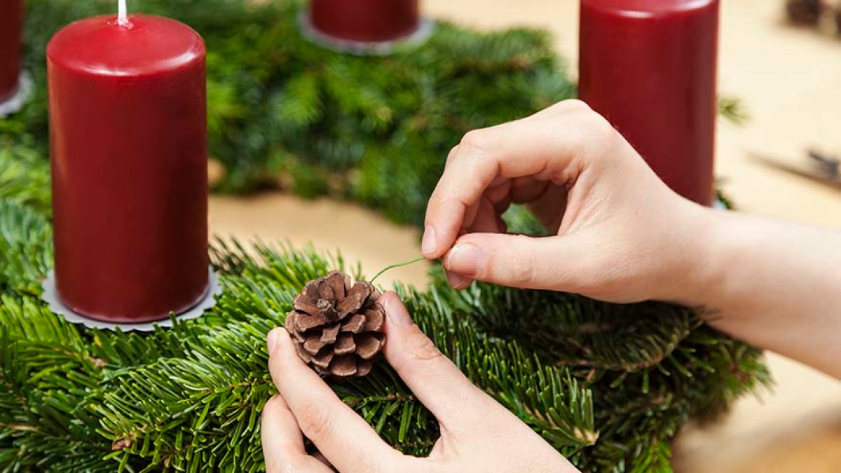 Adventskranz basteln, mit Tannenzapfen schmücken