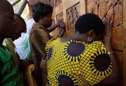 Ugandan women pray at the relief doors of the Martyrs shrine in Namugongo &#8211; ar