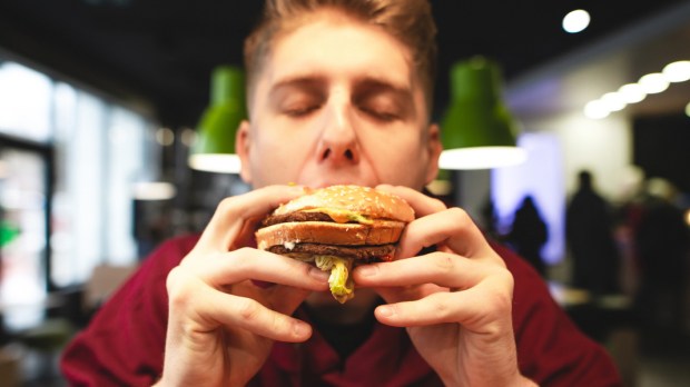 web3-young-man-eats-a-delicious-large-burger-with-his-eyes-closed-and-delights.-close-up-portrait-of-a-funny-man-biting-a-burger.-harmful-delicious-food-at-the-fast-food-restaurant-shutt.jpg