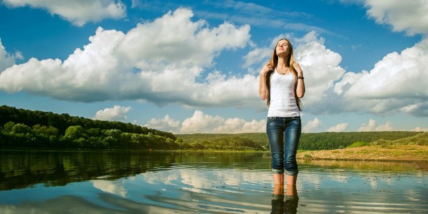 mujer bañando sus pies en un río
