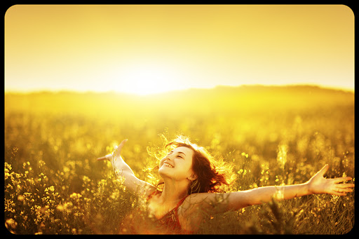 Young happy woman in canola field on sunset. © IBushuev / Shutterstock