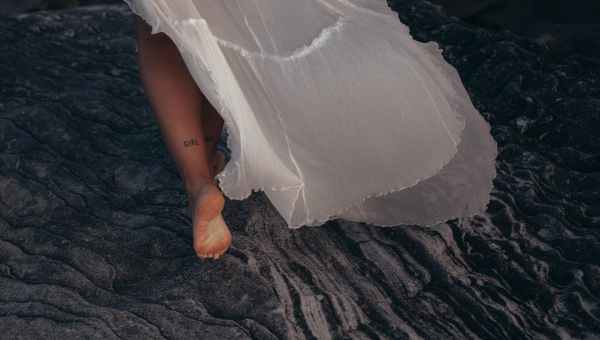 woman wearing white dress walking on sand