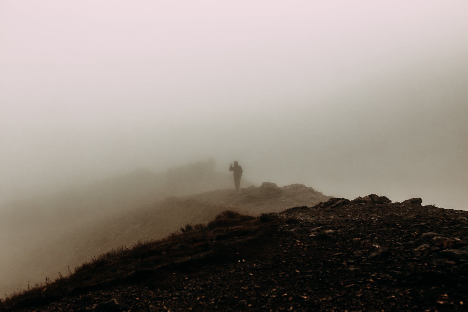 silhouette of person standing on hilltop in haze