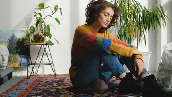 lady sitting near paintings on floor in studio