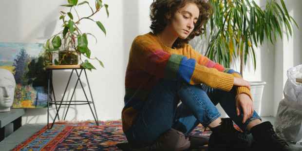 lady sitting near paintings on floor in studio