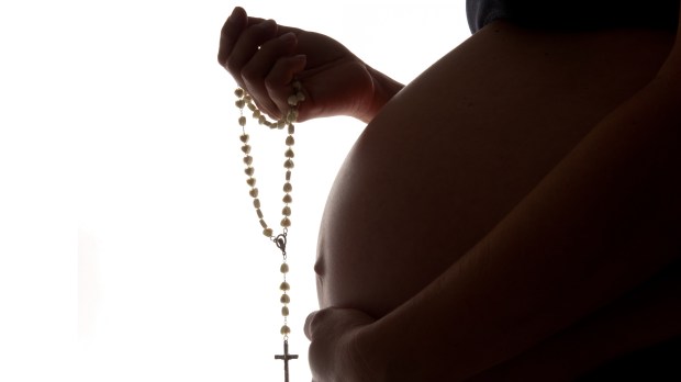 Nine-months-pregnancy-holding-a-rosary-shutterstock