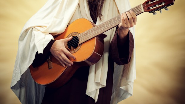 Man wearing Jesus Christ costume and plays guitar
