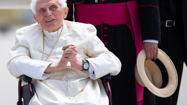 Nella foto Benedetto XVI sulla sedia a rotelle con le mani giunte