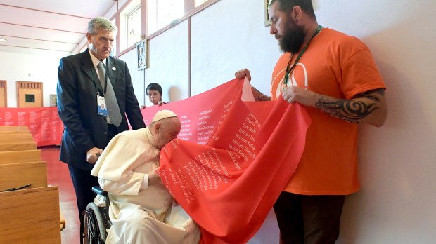 Pope Francis kissing a banner with names of victims of abuse committed at residential schools run by the Catholic Church,