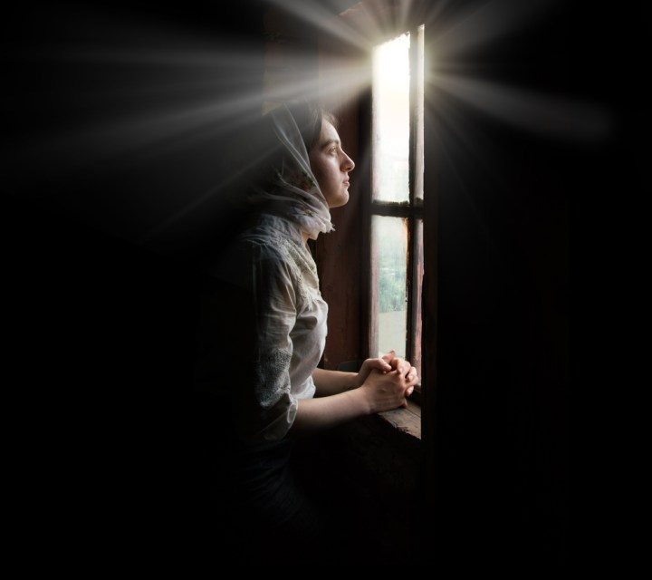 kobieta zbliża się do okna pełnego światła