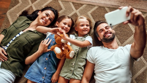 rodzina leży razem na podłodze i robi sobie zdjęcie smartfonem