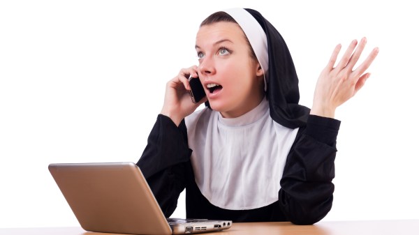 SUORA PARLA AL TELEFONO DAVANTI AL PC PORTATILE