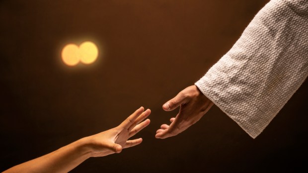 Jesus Christ reaching out to help those in need in a room lit with warm lights