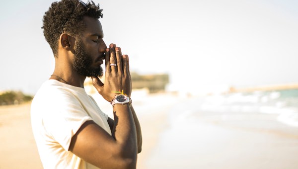 Homem rezando na praia