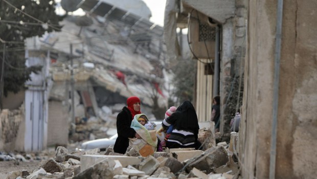 Syrian women and children sit wrapped in blankets outside collapsed buildings on February 7, 2023, in the town of Jandairis, in the rebel-held part of Aleppo province, as search and rescue operations continue following a deadly earthquake. - The death toll from the massive earthquake that struck Turkey and Syria rose above 8,300, official data showed, with rescue workers still searching for trapped survivors. (Photo by Bakr ALKASEM / AFP) - EN_01553763_1096.jpg
