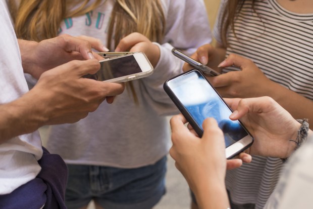 group of young people with mobile phones on the street