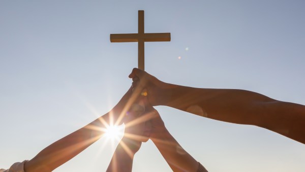 Kilka osób trzyma krzyż